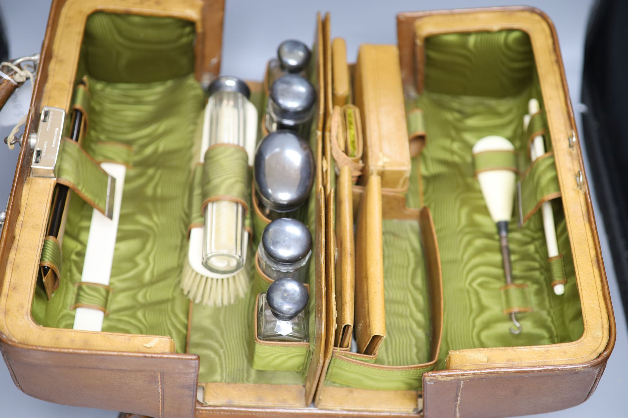 A travelling leather toilet case by H. Greaves, Birmingham, with six silver mounted glass toilet jars, Birmingham and London, 1897,